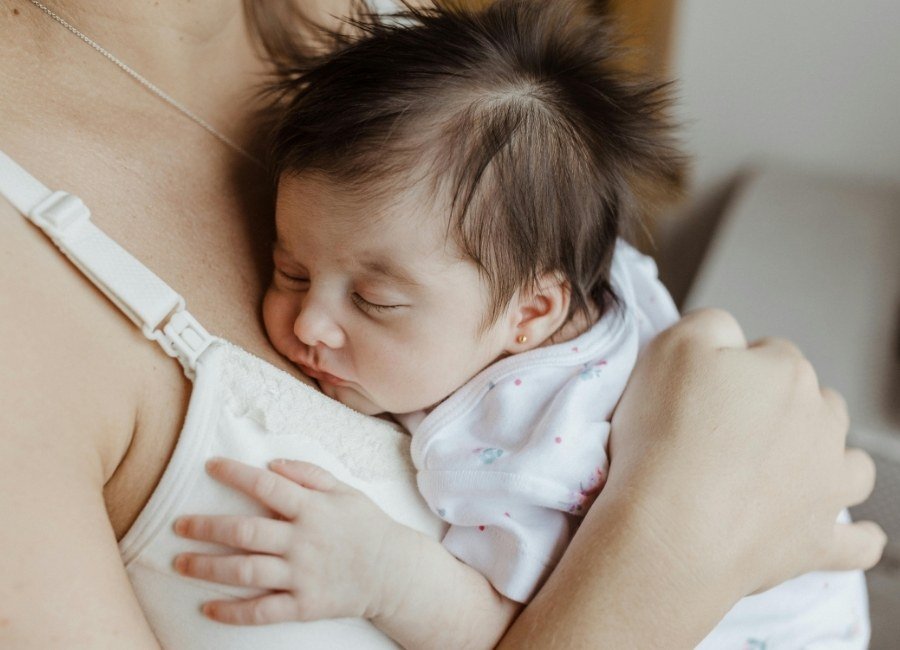 Bebe dormindo no colo da mãe fortalecendo o vinculo afetivo.