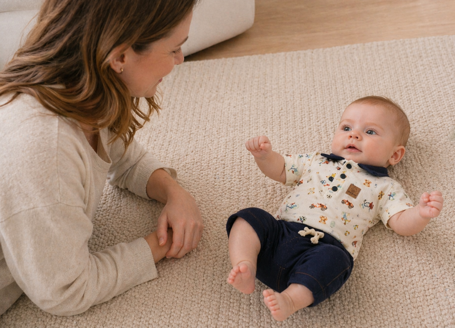Mãe observando bebê se movimentando livremente no chão, estimulando o desenvolvimento motor com segurança